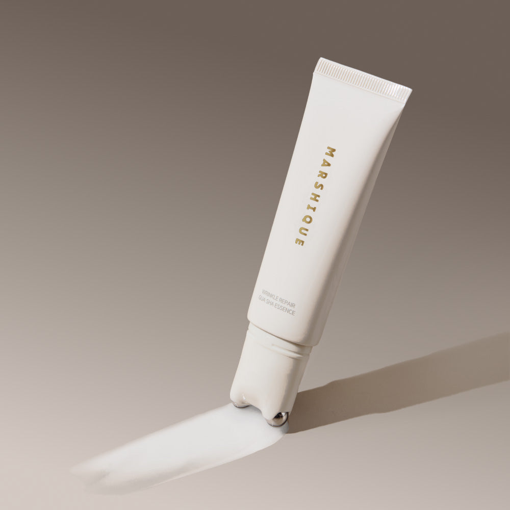 MARSHIQUE Wrinkle Repair Guasha Essence 45ml, tube blanc sur fond beige, mise en scène beauté.