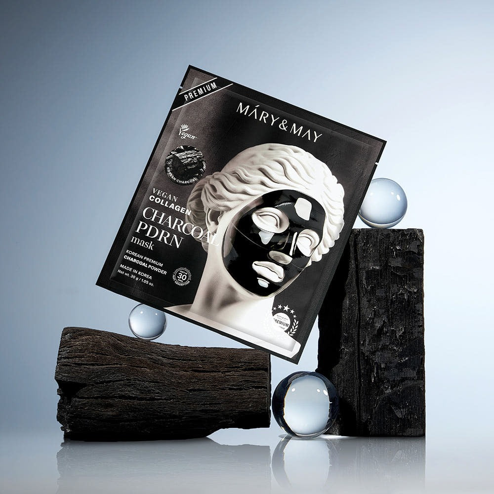 MARY&MAY Vegan Collagen Charcoal PDRN Gel Mask (4 Sheets) en boîte sur fond de bois et verre, produit de soins de la peau.