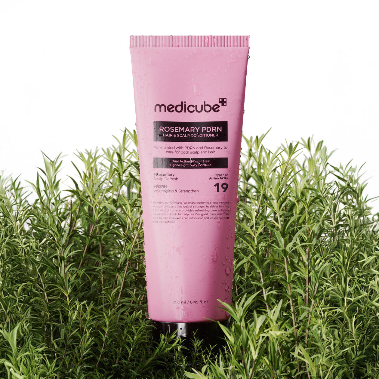 MEDICUBE Rosemary PDRN Hair & Scalp Conditioner 250ml, tube rose de la marque mediciube, posé dans l’herbe verte