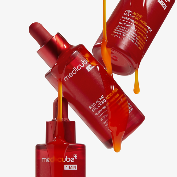 Image de trois flacons MEDICUBE Red Acne Succinic Acid Peel 40g avec liquide orange versé. Soin acné efficace et innovant.
