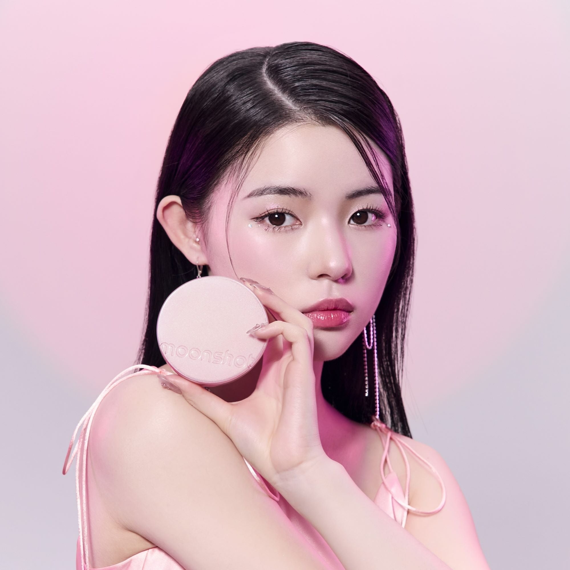 MOONSHOT Conscious Fit Cushion Foundation Pink Moon Edition, marque MOONSHOT, femme tenant la poudre sur fond rose