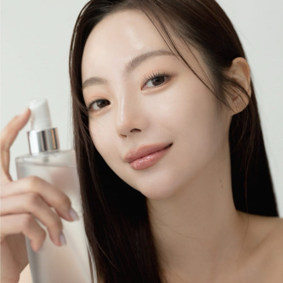 Femme souriante tenant QUA-T Toner 200ml, produit cosmétique pour soin de la peau, confidentialité respectée