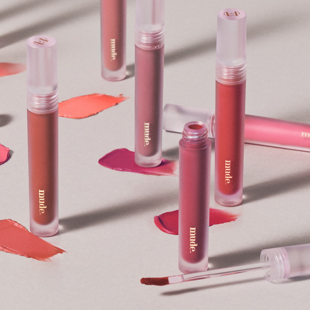 Mude Mood Soft Blur Tint de Mude, maquillage lèvres aux tons rose; produits sur fond crème avec textures.