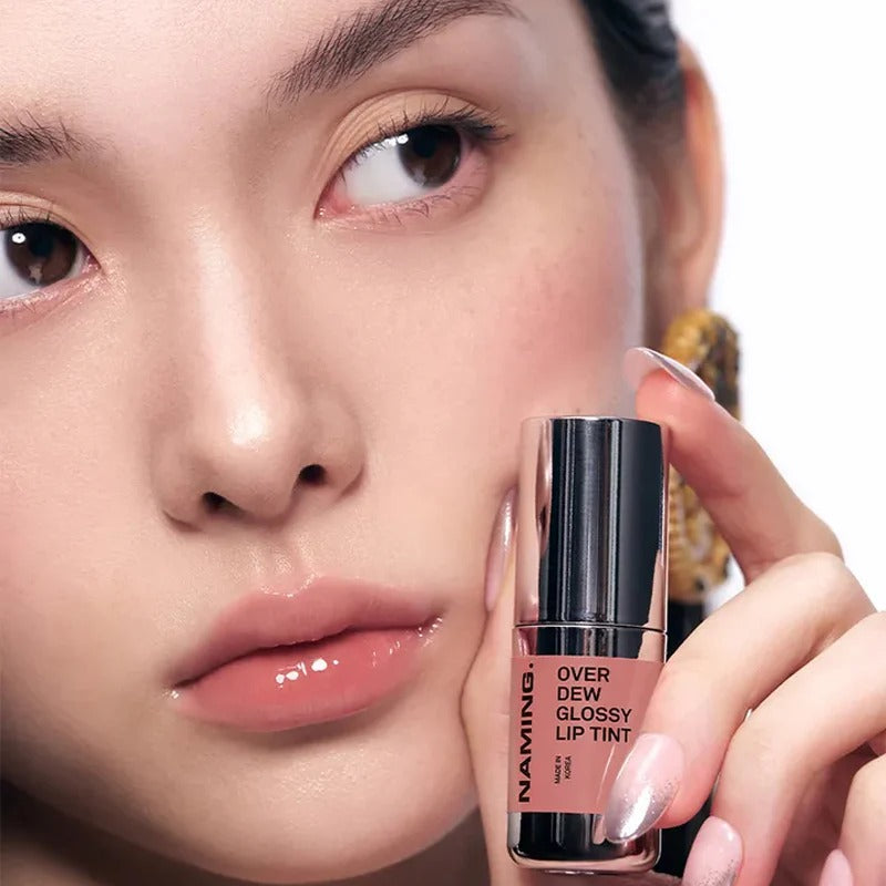 NAMING Overdew Glossy Lip Tint, marque NAMING, sur lèvres brillantes en gros plan, main tenant le tube