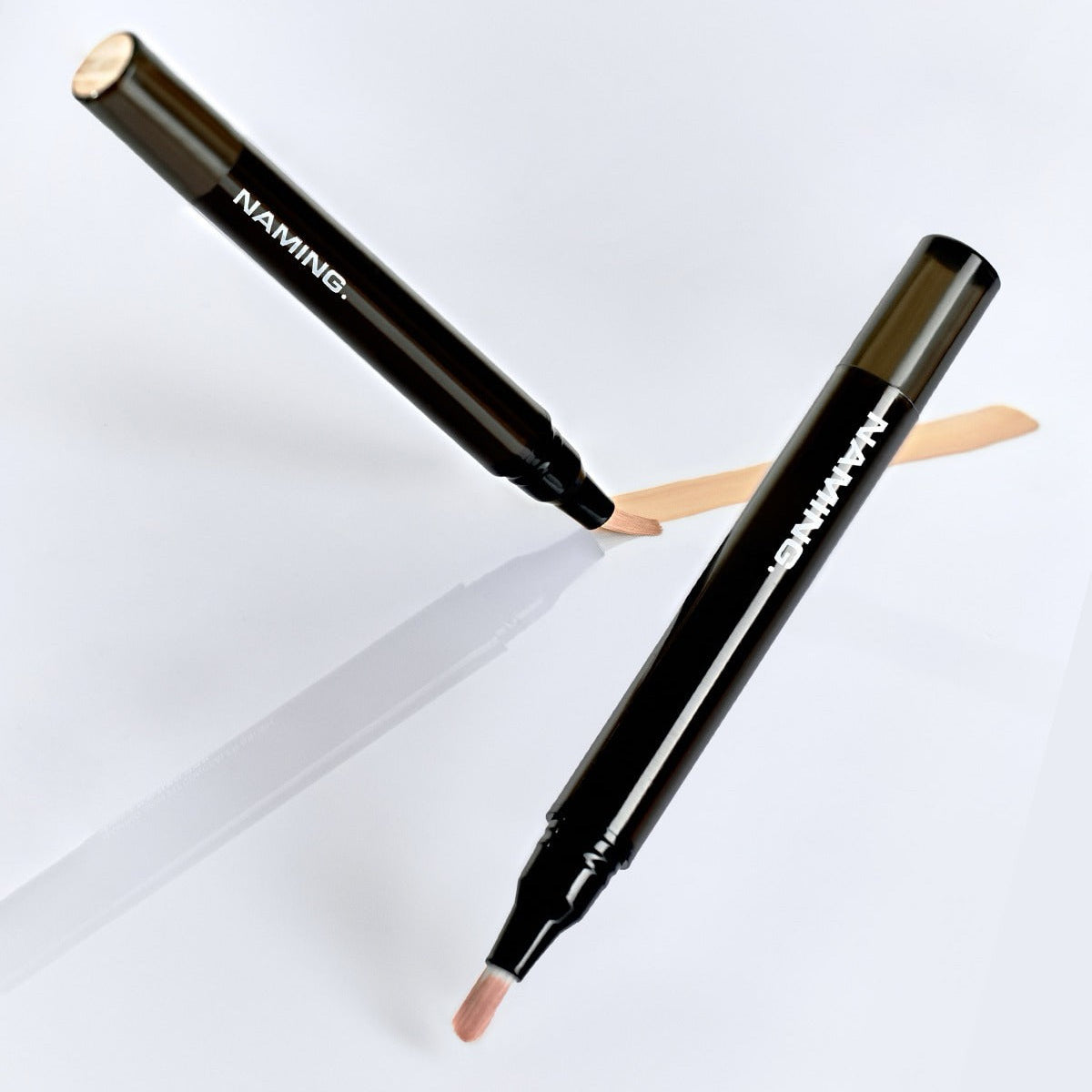 NAMING Skin Fit Concealer Brush de la marque NAMING, brosses maquillage noires sur fond blanc, avec swatches crème.