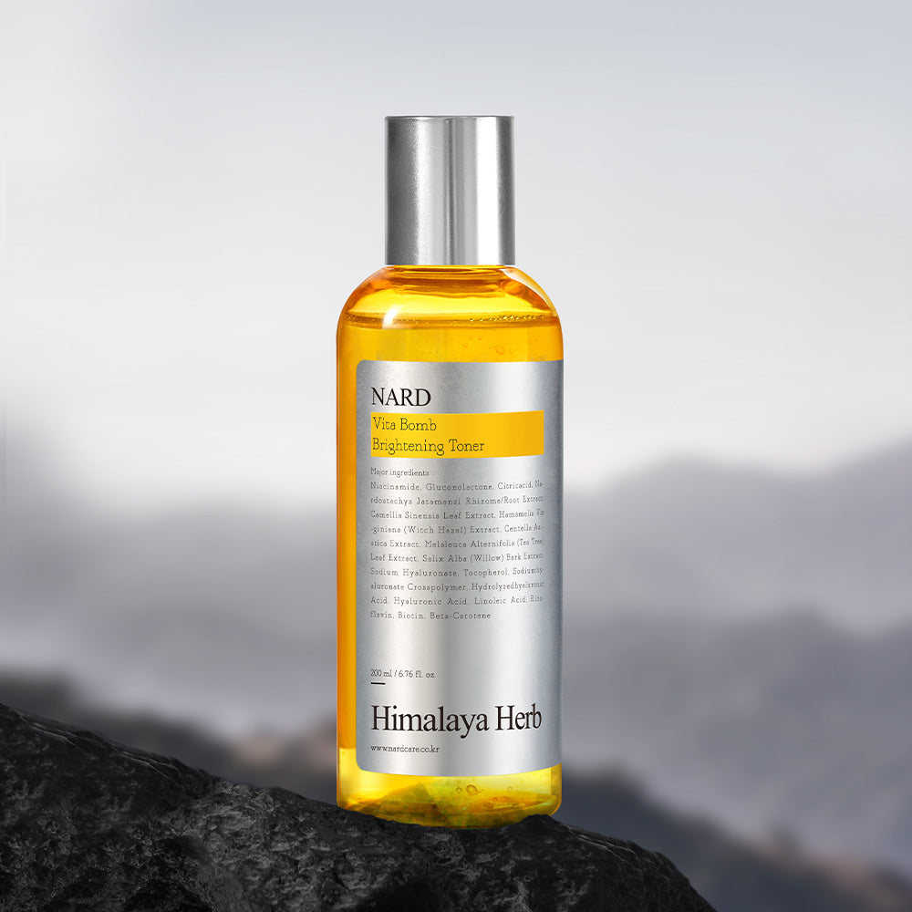 NARD Vita Balm Brightening Toner 200ml de NARD, flacon orange sur rocher avec fond montagne flou