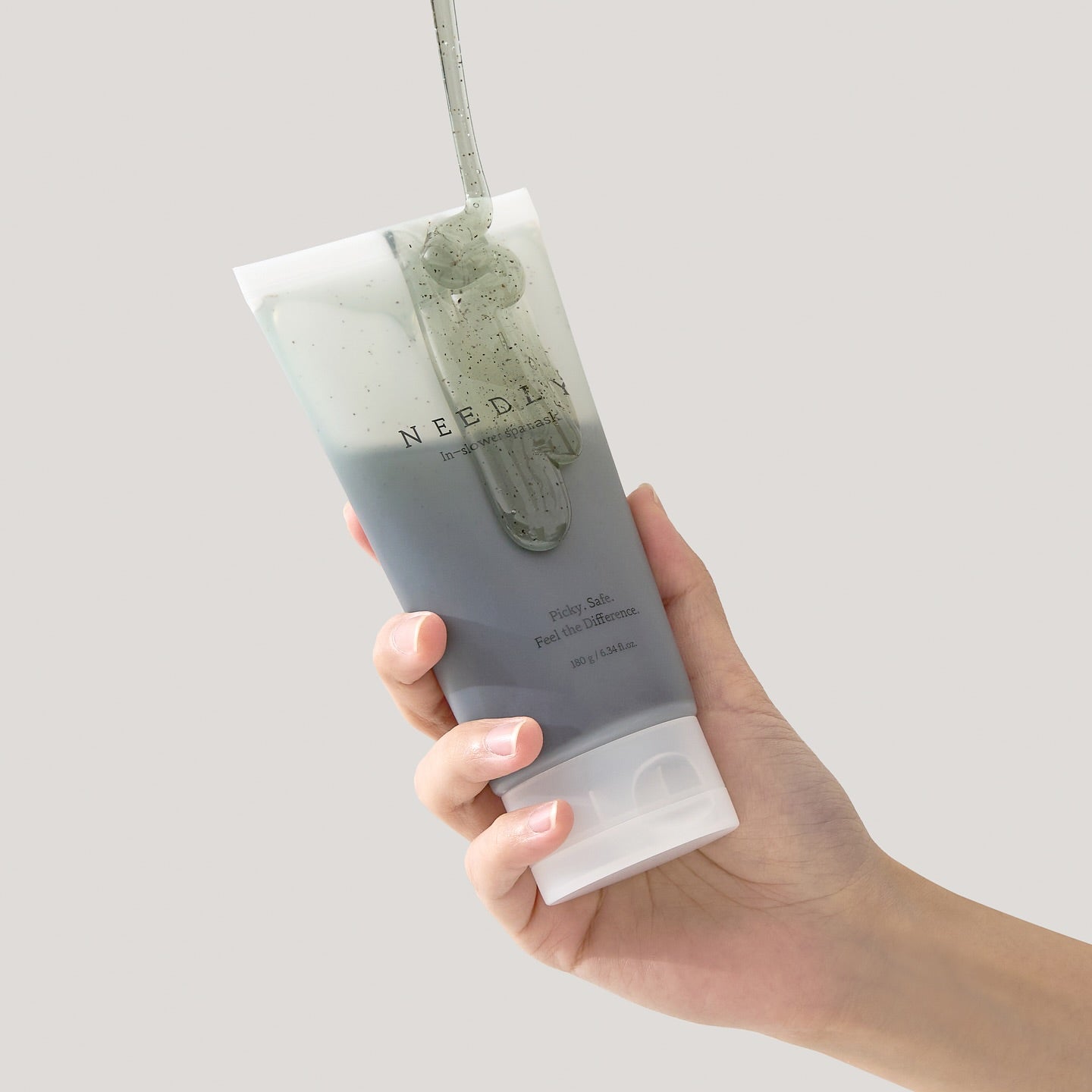 Main tenant NEEDLY Ishower Spa Mask 180g, tube crème en douche, marque NEEDLY, visuel blanc/vert.