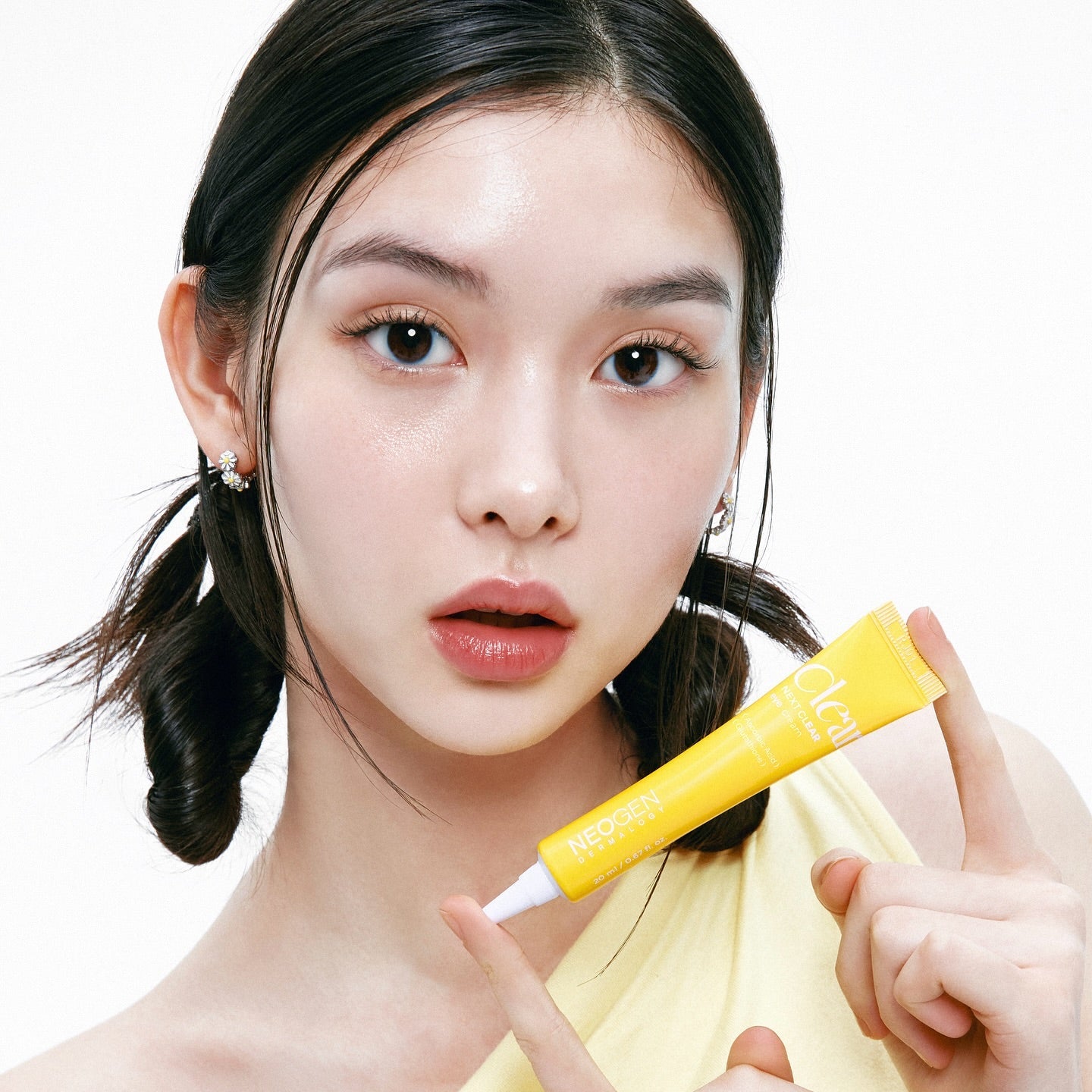 Jeune femme tenant un tube de NEOGEN Next Clear Eye Cream 20ml, idéale pour un soin des yeux lumineux.