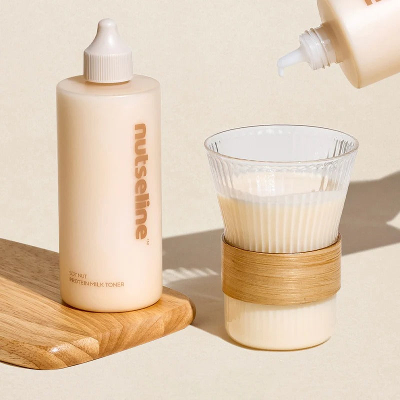 NUTSELINE Soy Nut Protein Milk Toner 300ml, flacon crème sur table bois, contexte beauté avec verseur et verre en arrière-plan.