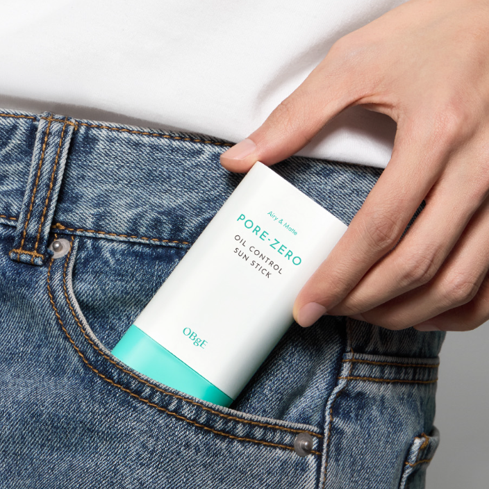 OBGE Pore Zero Oil Control Sun Stick de la marque OBGE, appliqué sur un jean, main tenant le stick anti-brillance