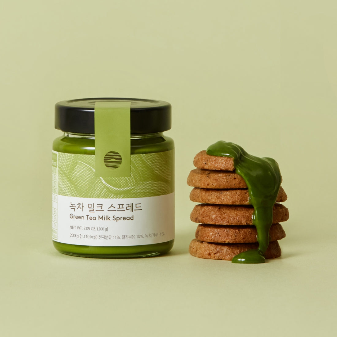 OSULLOC Green Tea Milk Spread 200g : pot vert à côté de biscuits tartinés, ambiance minimaliste en studio.