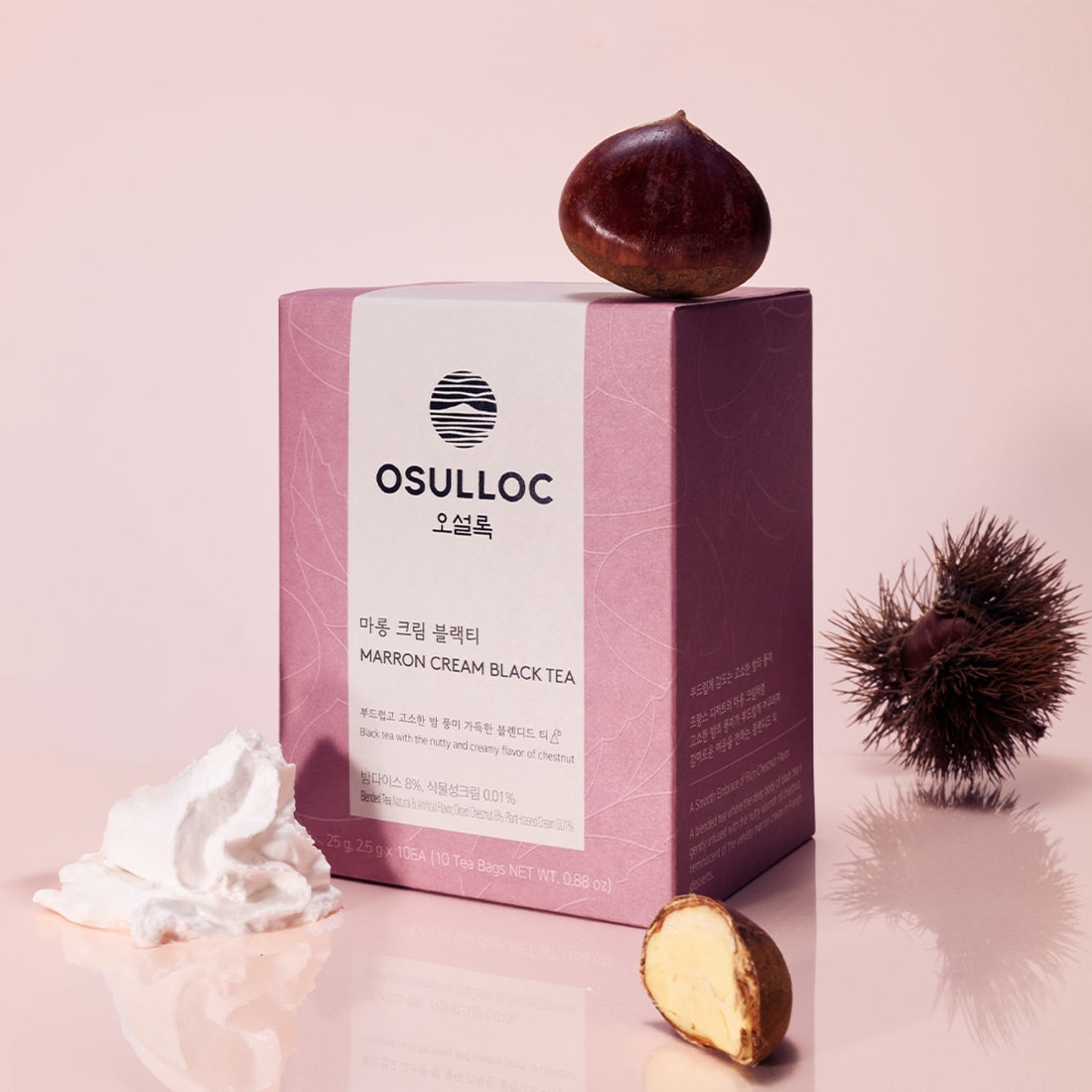 Décris l'image en français : OSULLOC Marron Cream Black Tea 10 p., coffret et marron, fond rose, décor crème.