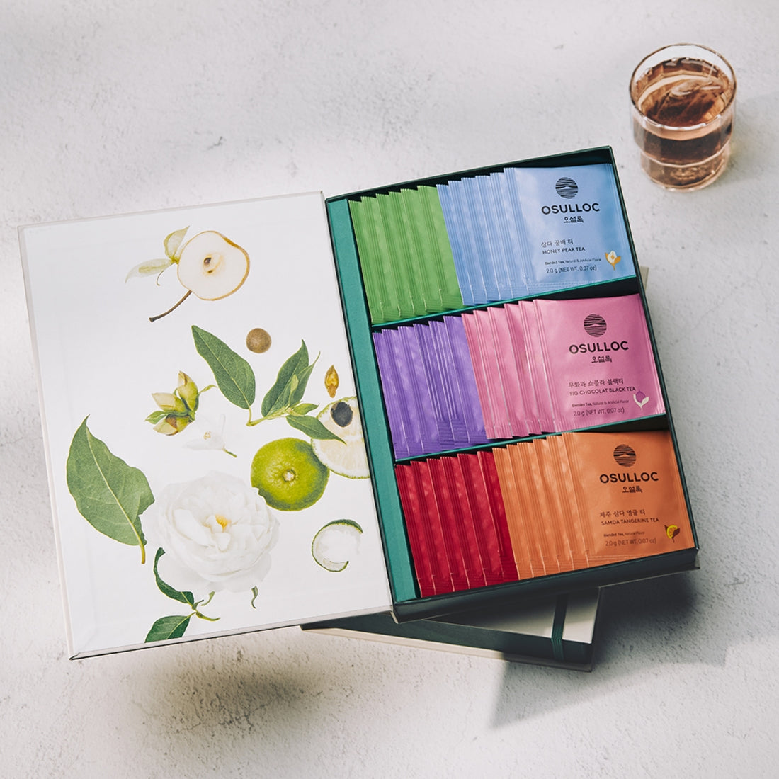 OSULLOC Tea Variation O 6 types, coffret de thés multicolores sur table avec fleurs et tasse, style photo produit.