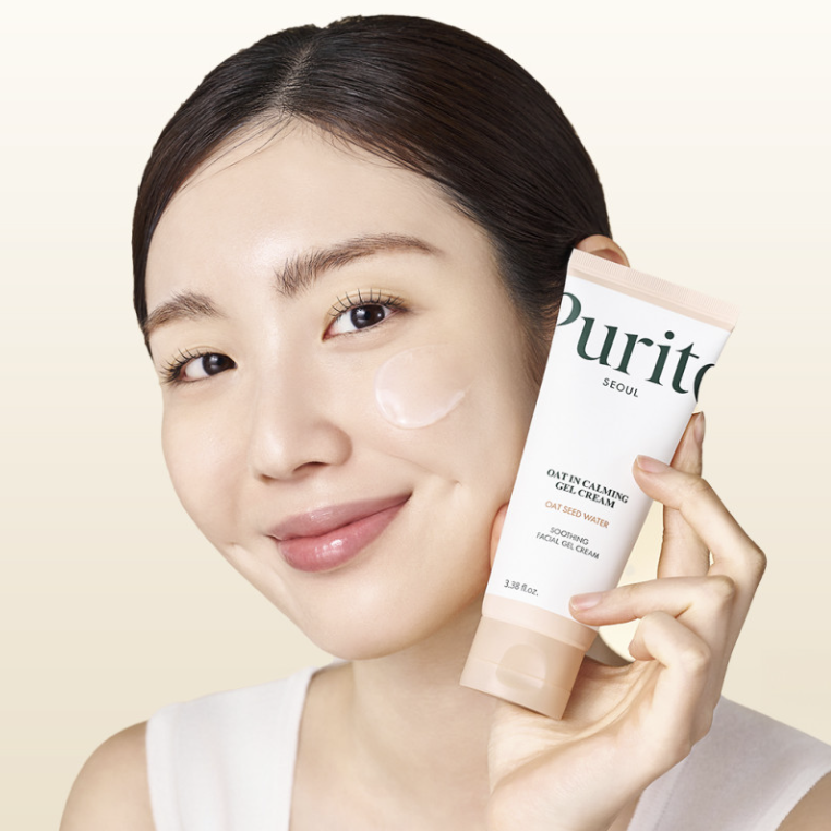 Décris l'image en français : PURITO Oat In Calming Gel Cream 100ml, crème apaisante Purito, visage tenant le tube sur fond clair.