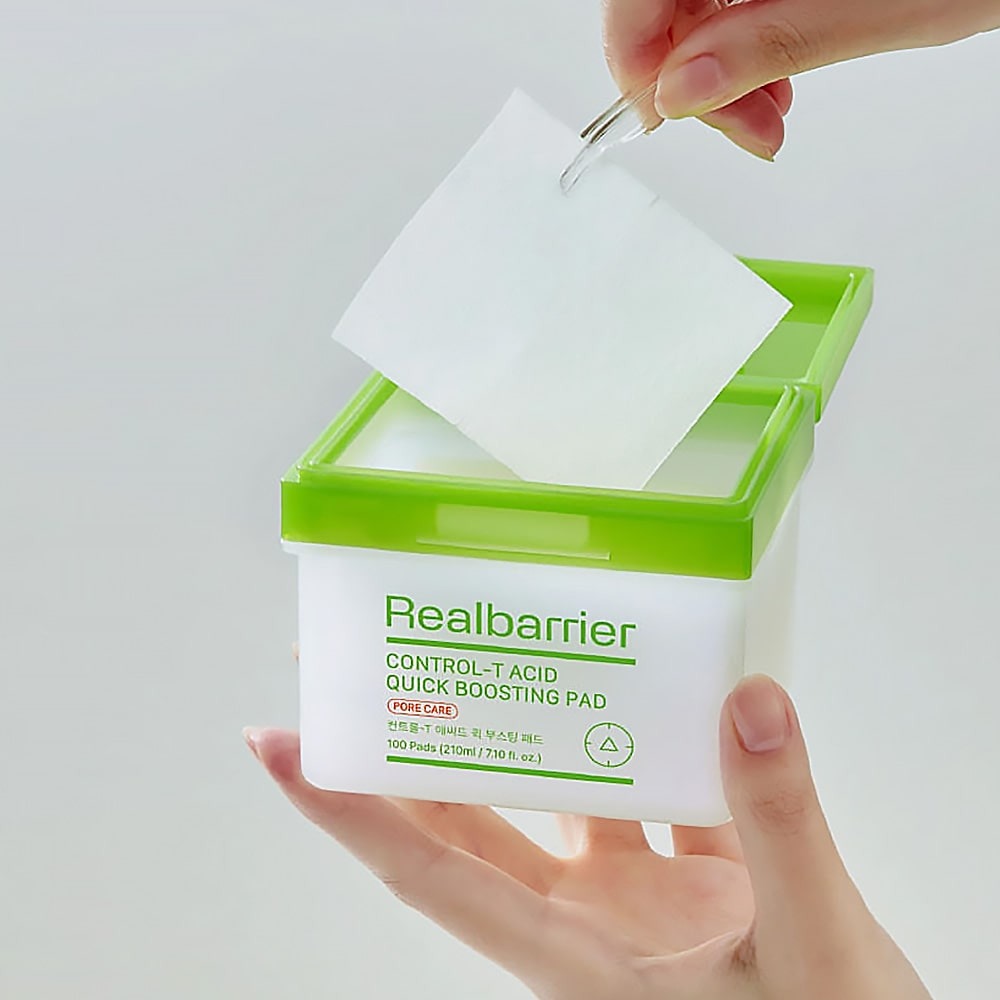 REAL BARRIER Control-T Acid Quick Boosting Pads 100 Sheets, marque Realbarrier : mains ouvrant un boîtier vert, contexte visuel produit.