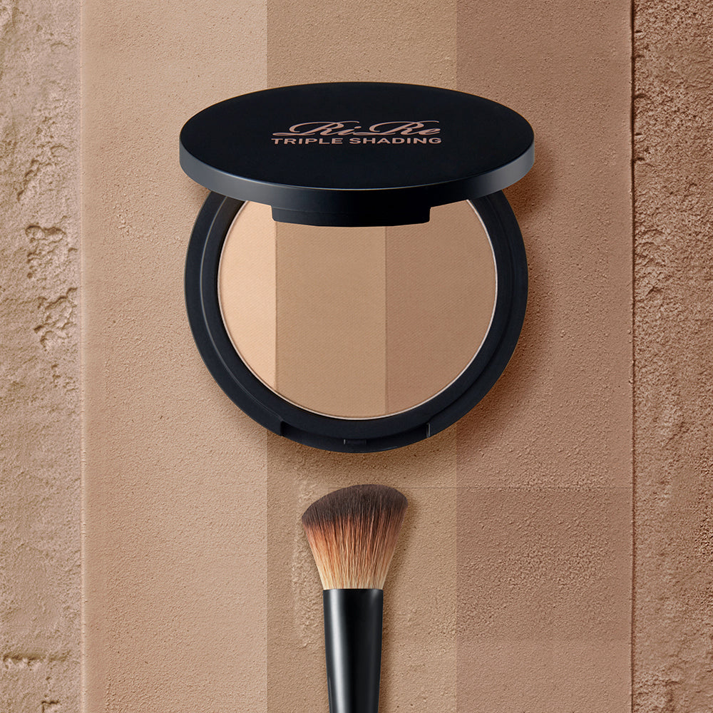 RIRE Triple Shading 9,5g de RIRE : poudre visage triple teinte en maquillage, sur fond beige avec pinceau