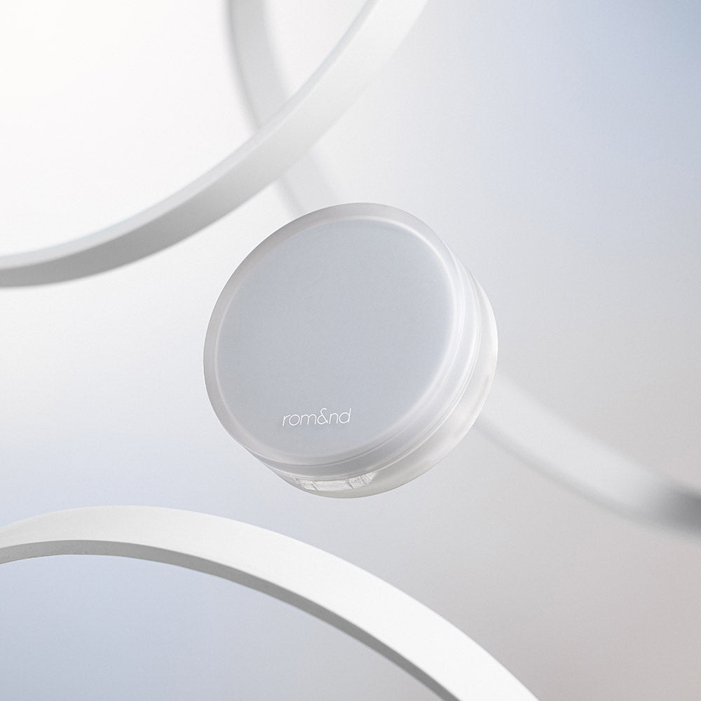 ROMAND Nu Zero Cushion, boîte de coussin crème blanche sur fond minimal avec couvercle et miroir, style épuré.