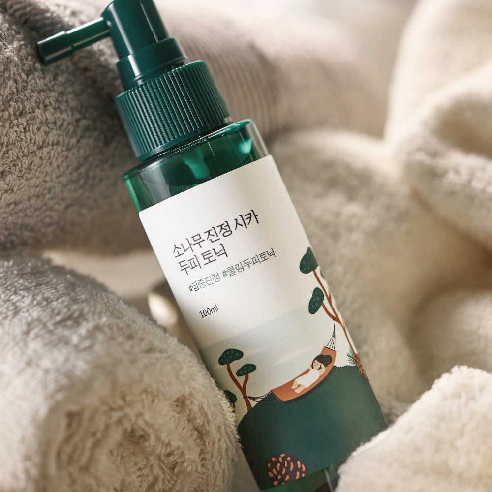 ROUND LAB Pine Calming Cica Hair Tonic 100ml sur serviette douce, marque ROUND LAB, contexte spa à la maison