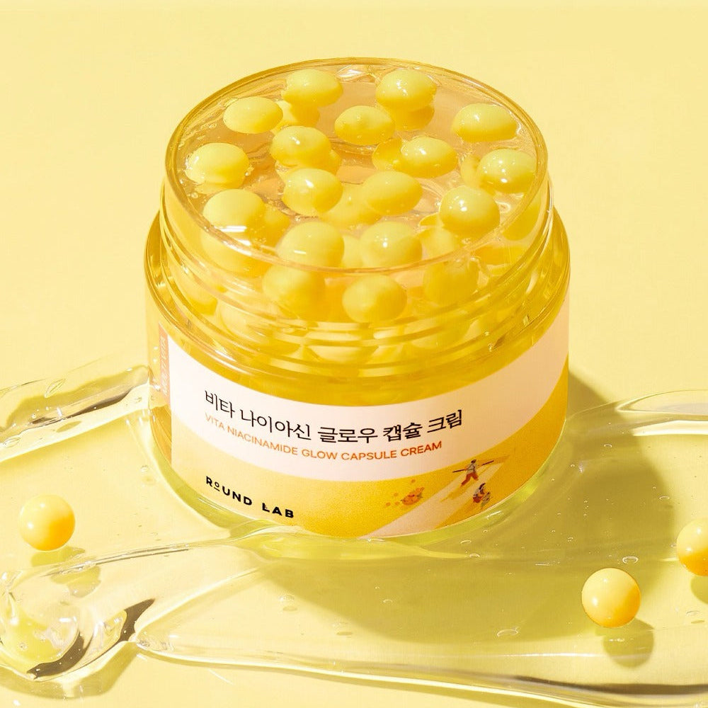 ROUND LAB Vita Niacin Glow Capsule Cream 50ml, pot crème jaune avec capsules, sur fond lumineux jaune, marque présentée