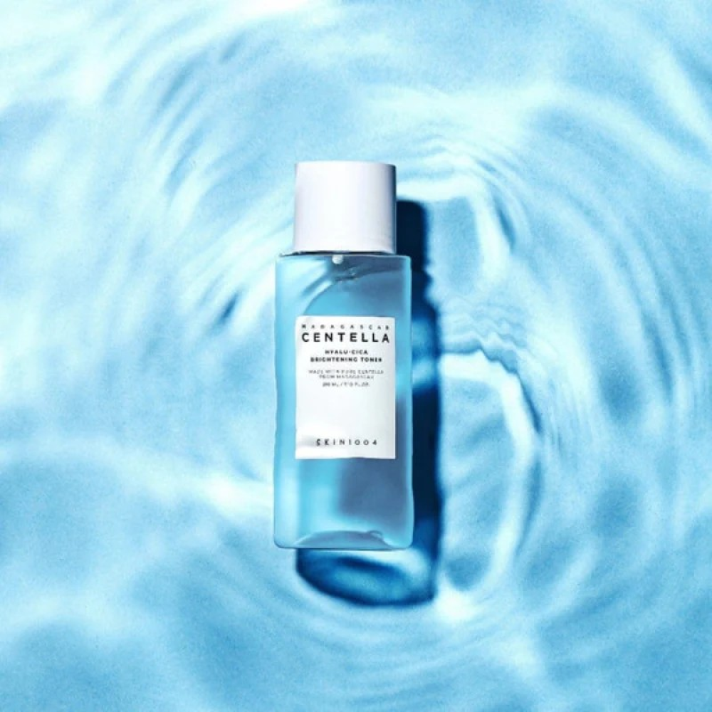 SKIN1004 Madagascar Centella Hyalu-Cica Radiance Toner 210ml de SKIN1004, flacon bleu sur fond bleu textures d’eau.