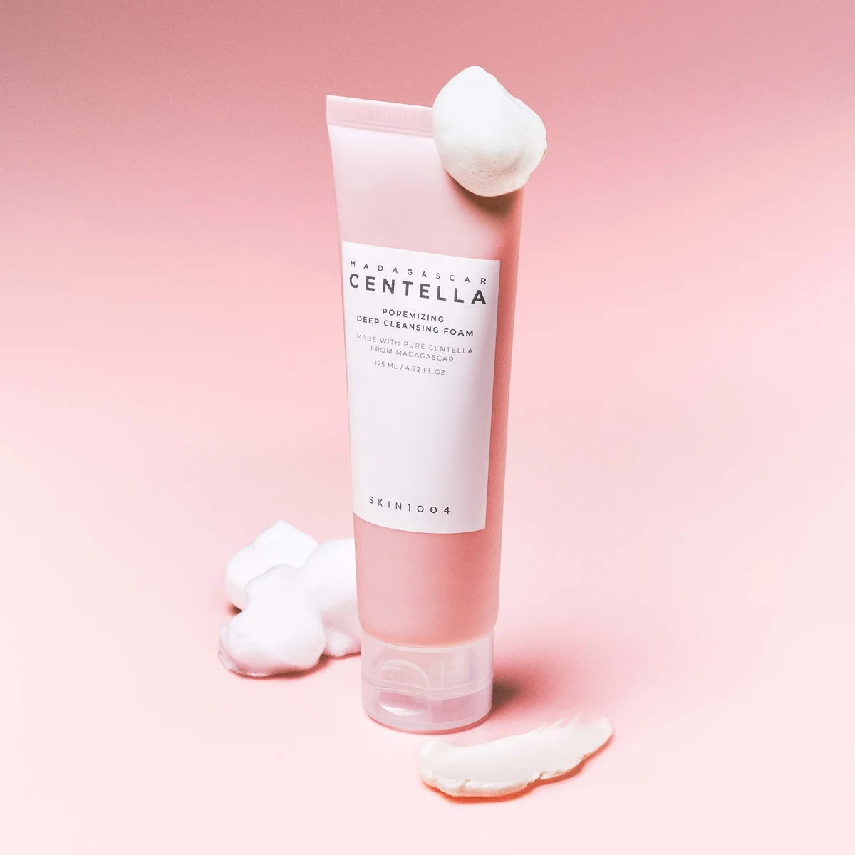 SKIN1004 Madagascar Centella Poremizing Deep Cleansing Foam 125ml en flacon crème sur fond rose, avec mousse.