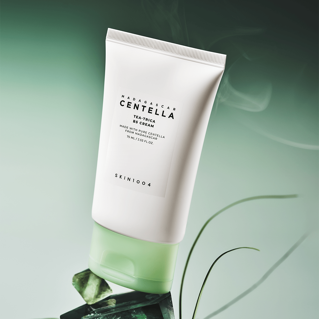 Décris l'image en français : SKIN1004 Madagascar Centella Tea-trica B5 Cream 75ml SKIN1004 sur fond vert apaisant.