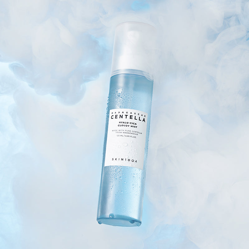Vaporisateur 120ml SKIN1004 Madagascar Centella Hyaluronic Acid Cloudy Mist sur fond nuageux bleu, soin hydratant visage revitalisant.