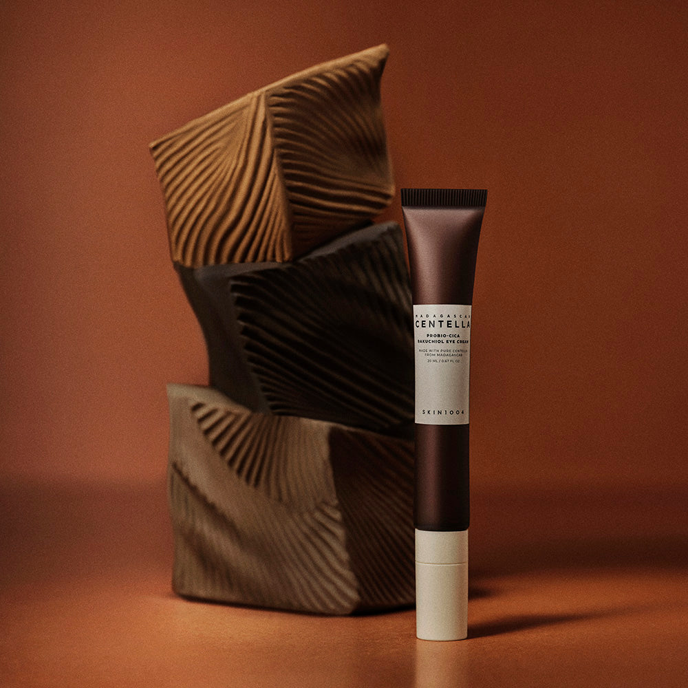 Crème pour les yeux SKIN1004 Madagascar Centella Probio-cica Bakuchiol 20ml sur fond artistique brun et texturé.