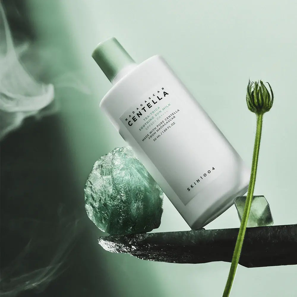 SKIN1004 Madagascar Centella Tea-trica Soothing Sun Milk 50ml sur fond vert, crème solaire apaisante en bouteille blanche.