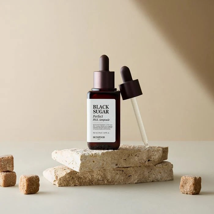 SKINFOOD Black Sugar Perfect PHA Ampoule 50ml, flacon et pipette sur socles, ambiance beige, look skincare.