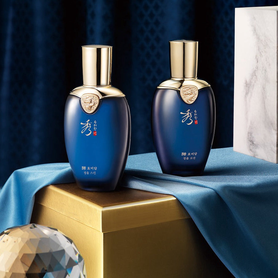 Deux bouteilles de SOORYEHAN Hyobidam Jeongyul Skin 150ml posées sur une boîte dorée avec un fond élégant en bleu.