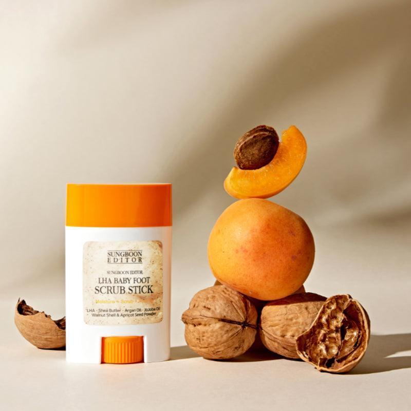 SUNGBOON EDITOR Laha Baby Foot Scrub Stick, pot orange sur fond beige avec abricots et noix, contexte spa.