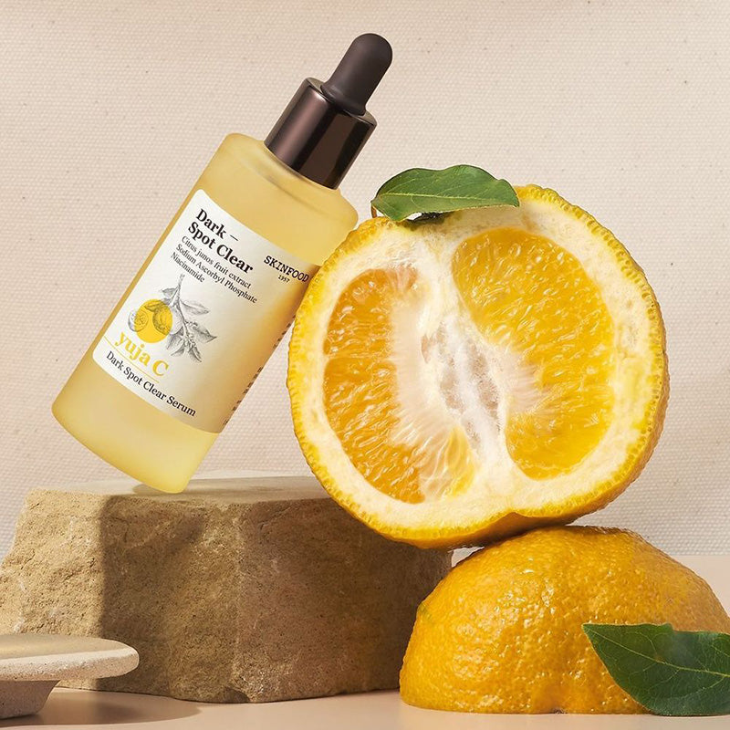 SKINFOOD Yuja C Dark Spot Clear Serum 50ml de Skinfood, flacon jaune sur agrumes, contexte visuel skincare