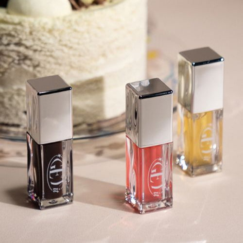 Décris l'image en français : TONY MOLY Get It Lip Oil de TONY MOLY, flacons brillants sur fond clair.