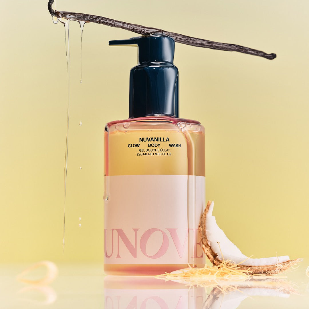 UNOVE Glow Body Wash 290ml de marque UNOVE, flacon rose sous un jet d’eau, fond jaune lumineux, produit en gros plan