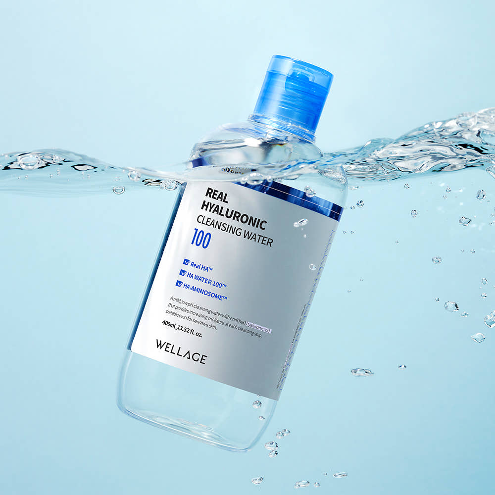 WELLAGE Real Hyaluronic Cleansing Water 400ml, bouteille en verre bleue avec éclaboussures d’eau, décor salle de bain.