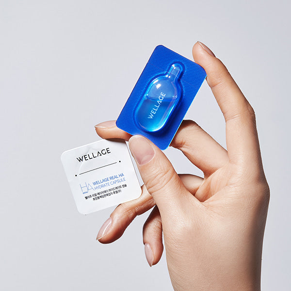 Main tenant WELLAGE Real Hyaluronic One Day kit, marques WELLAGE, sur fond clair, flacons bleus et sachet blanc
