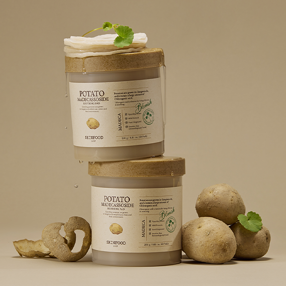 Décris l'image en français: SKINFOOD Potato Madecassoside Soothing Pad, bocaux sur fond beige avec pommes de terre et feuilles.