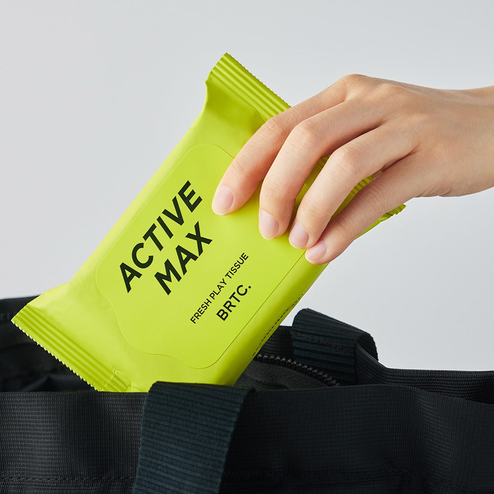 BRTC Homme Active Max Fresh Play Tissue 15 Sheets en main sortant d'un sac noir, emballage vert vif, 15 feuilles.
