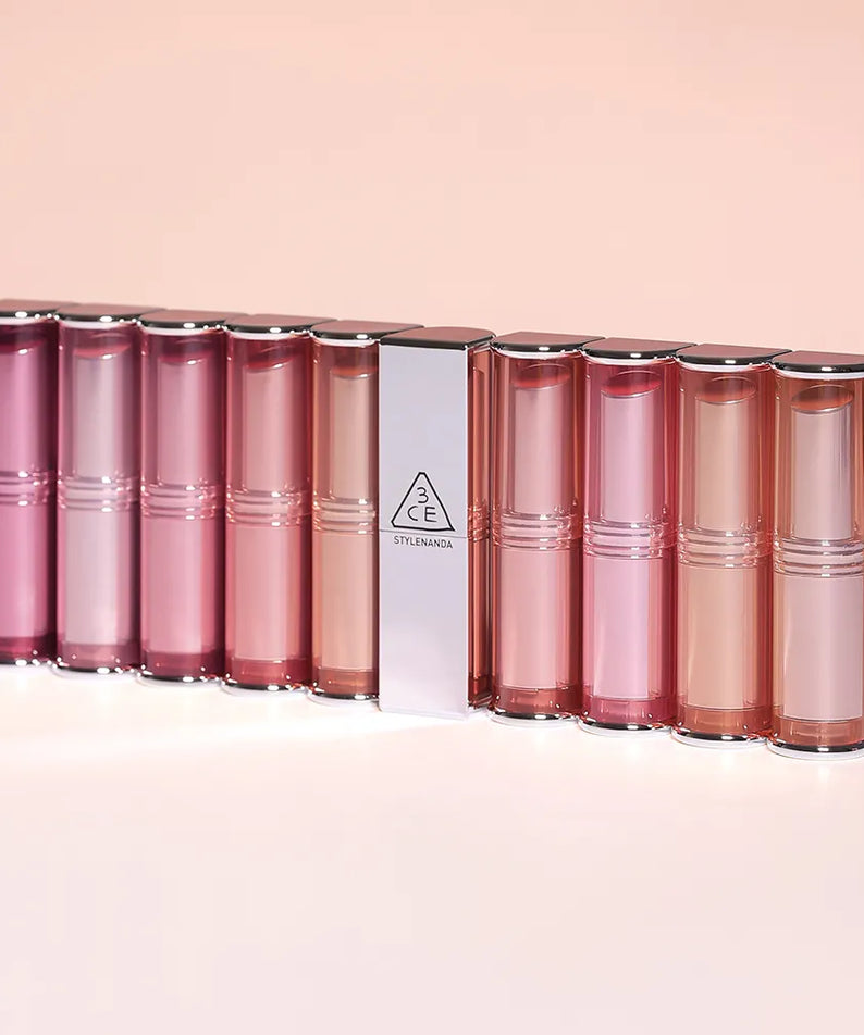 3CE Blur Matte Lipstick de 3CE, sur fond rose, présentoir de plusieurs baumes à lèvres, visuel maquillage.