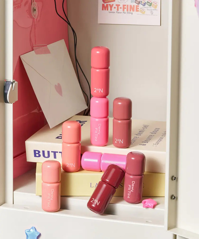 2AN Dewy Fit Tint 8 Colors, tubes de teinte dégradés roses sur étagère avec packaging, marque 2’N visible.