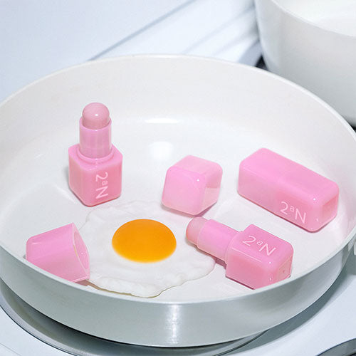 Décris l'image en français : 2AN Pocket Cotton Blurring Stick de la marque 2AN, stick rose sur plateau blanc.