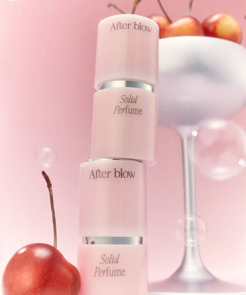 AFTER BLOW Solid Perfume 6.5g : flacon de parfum solide, décor fruits/verre, arrière-plan rose, ambiance lifestyle.