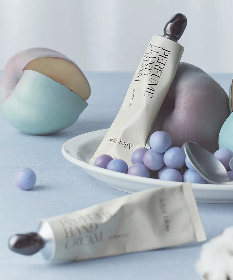 AFTER BLOW Perfume Hand Cream 50ml de la marque AFTER BLOW, tube sur fond pastel avec boules de cire et fleurs.