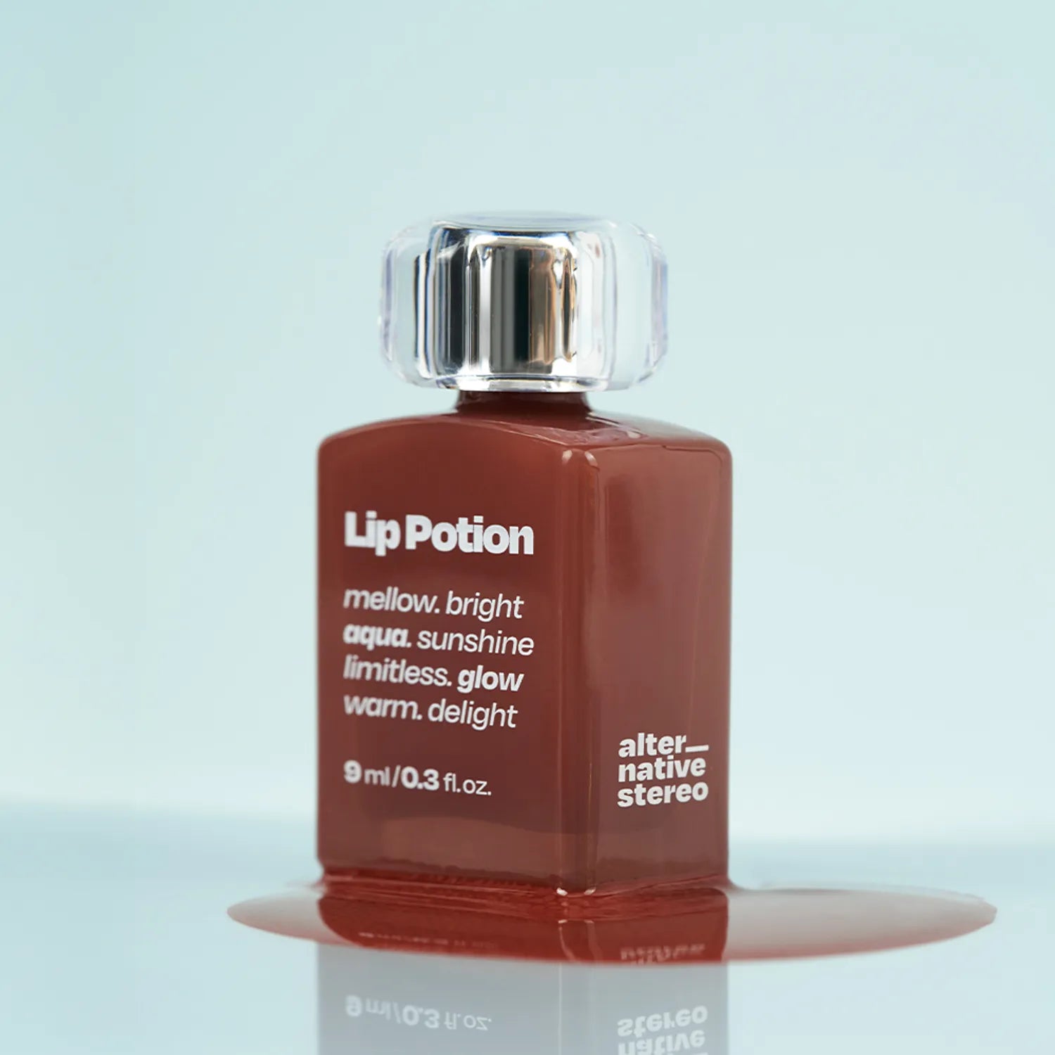 ALTERNATIVE STEREO Lip Potion Aqua Glow Tint, flacon et reflet en studio sur fond bleu clair, marque Alternative Stereo