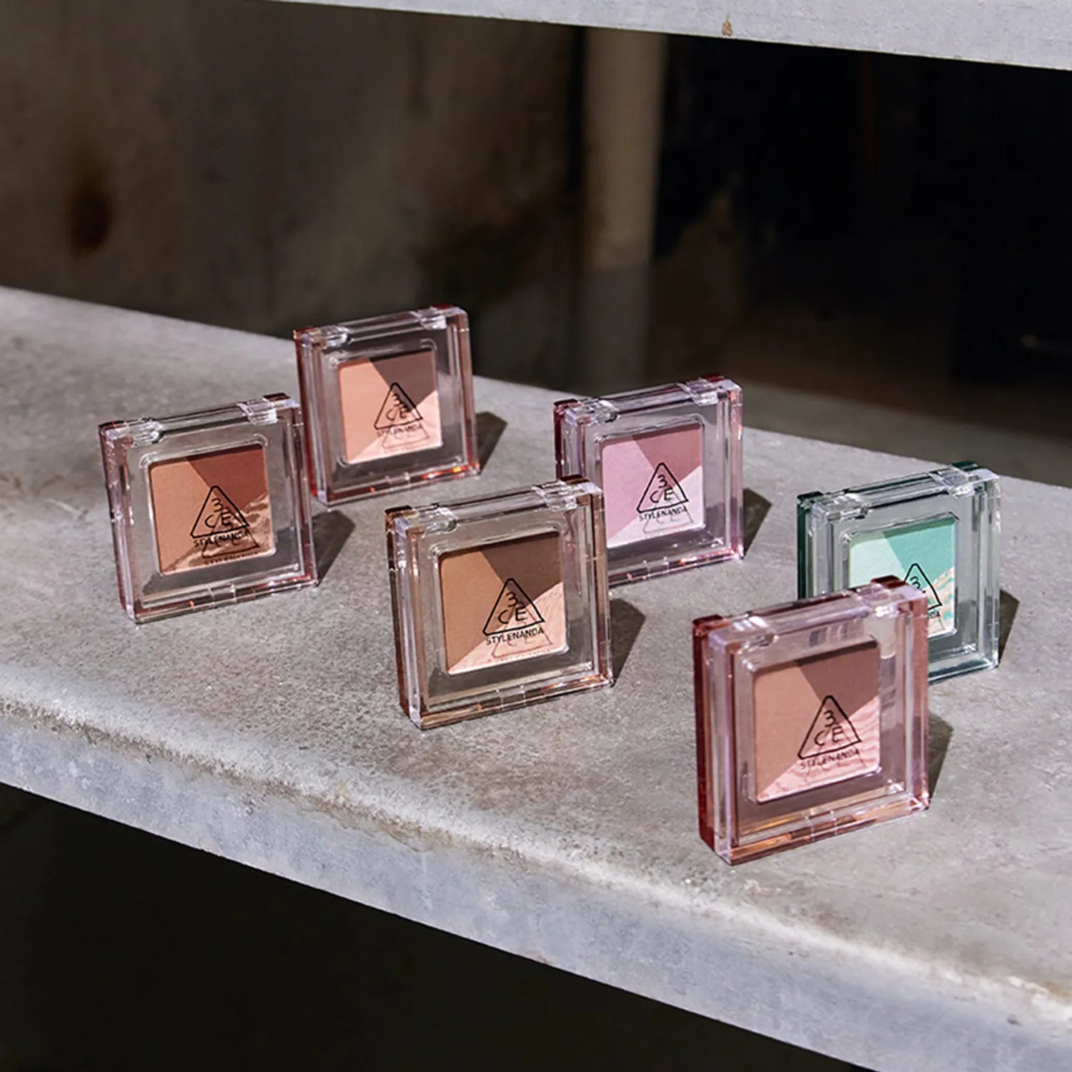 3CE Color Grid Eyeshadow : palette d’ombres dans un boîtier transparent, teintes nude et rose, présentation sur étagère.