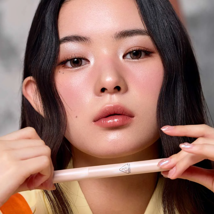 3CE Eye Switch Stick, maquillage yeux sur fond neutre : gros plan d’une femme tenant le stick 3CE.
