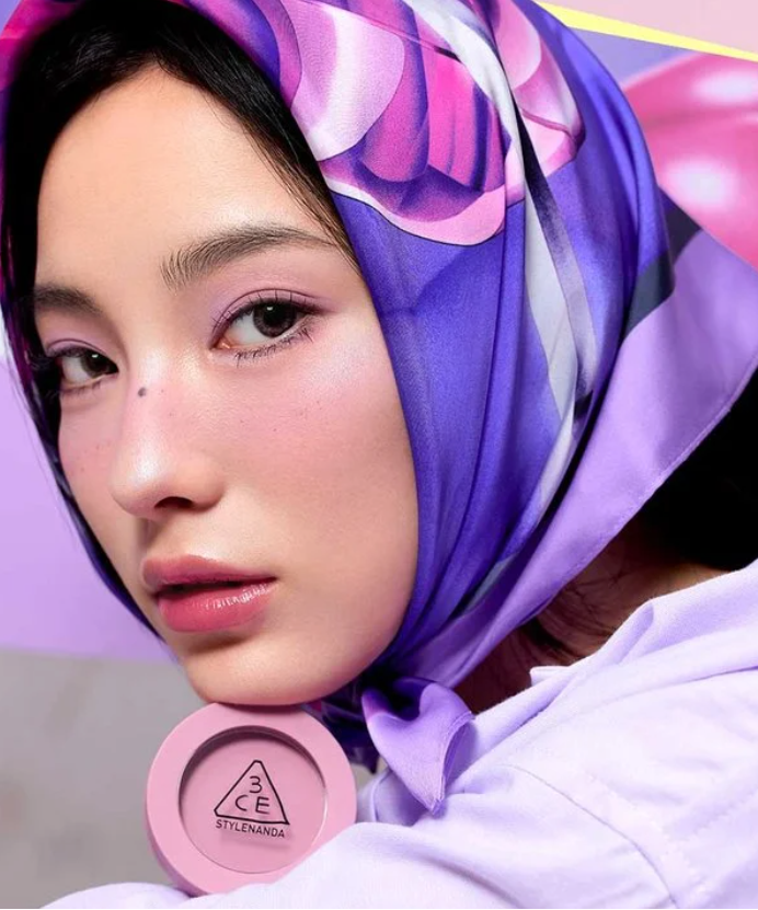 3CE Face Blush de 3CE sur maquillage: jeune femme au foulard violet, blush rose visible, intérieur lumineux