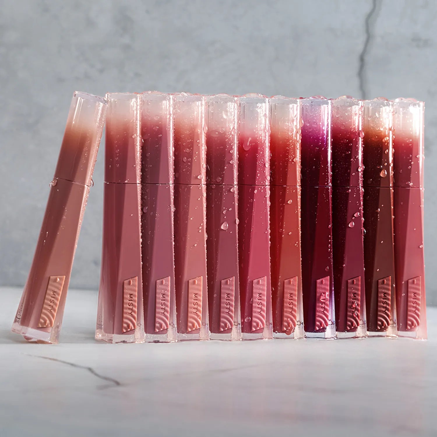 3CE Misty Lip Bare, gamme de baumes à lèvres nude en présentoir sur fond marbre, vue produit marque 3CE.