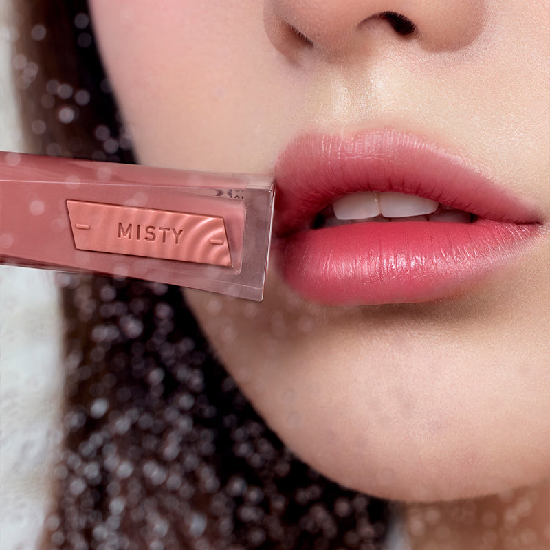 3CE Misty Lip Bare : gros plan lèvres rosées et maquillage, étui Misty de la marque 3CE, fond flou.